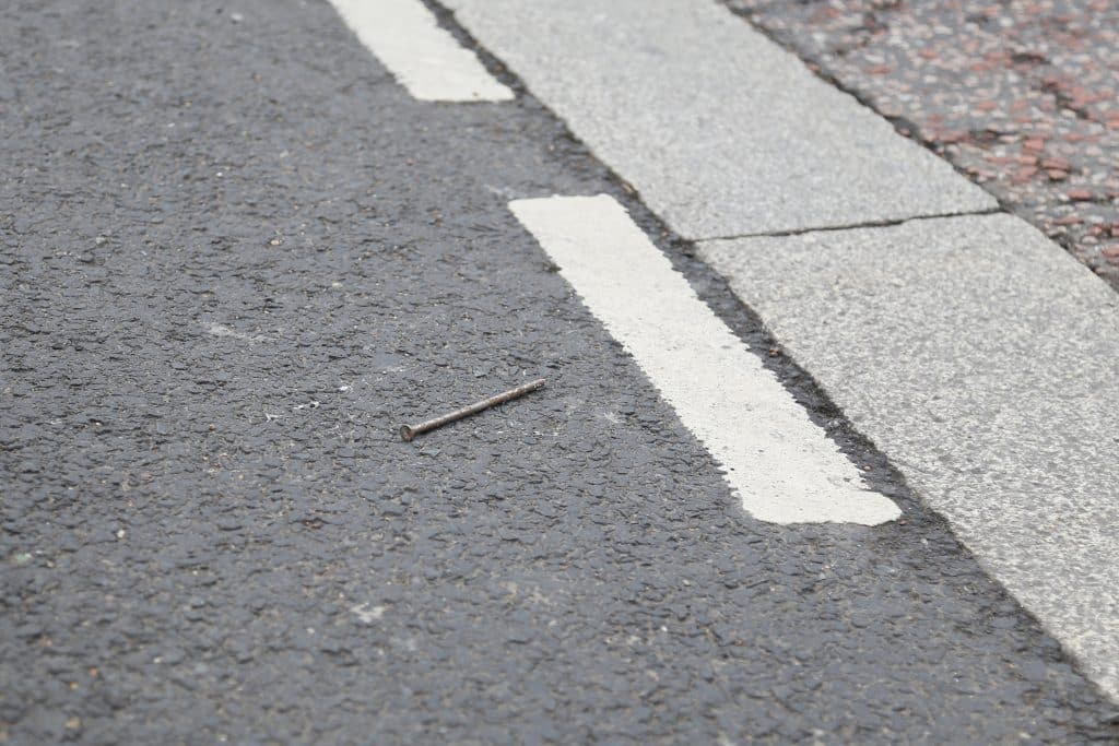 An image of a nail on a London road, a possible future tyre puncture. Part of artwork entitled Small Acts of Subtraction by David Rickard.
